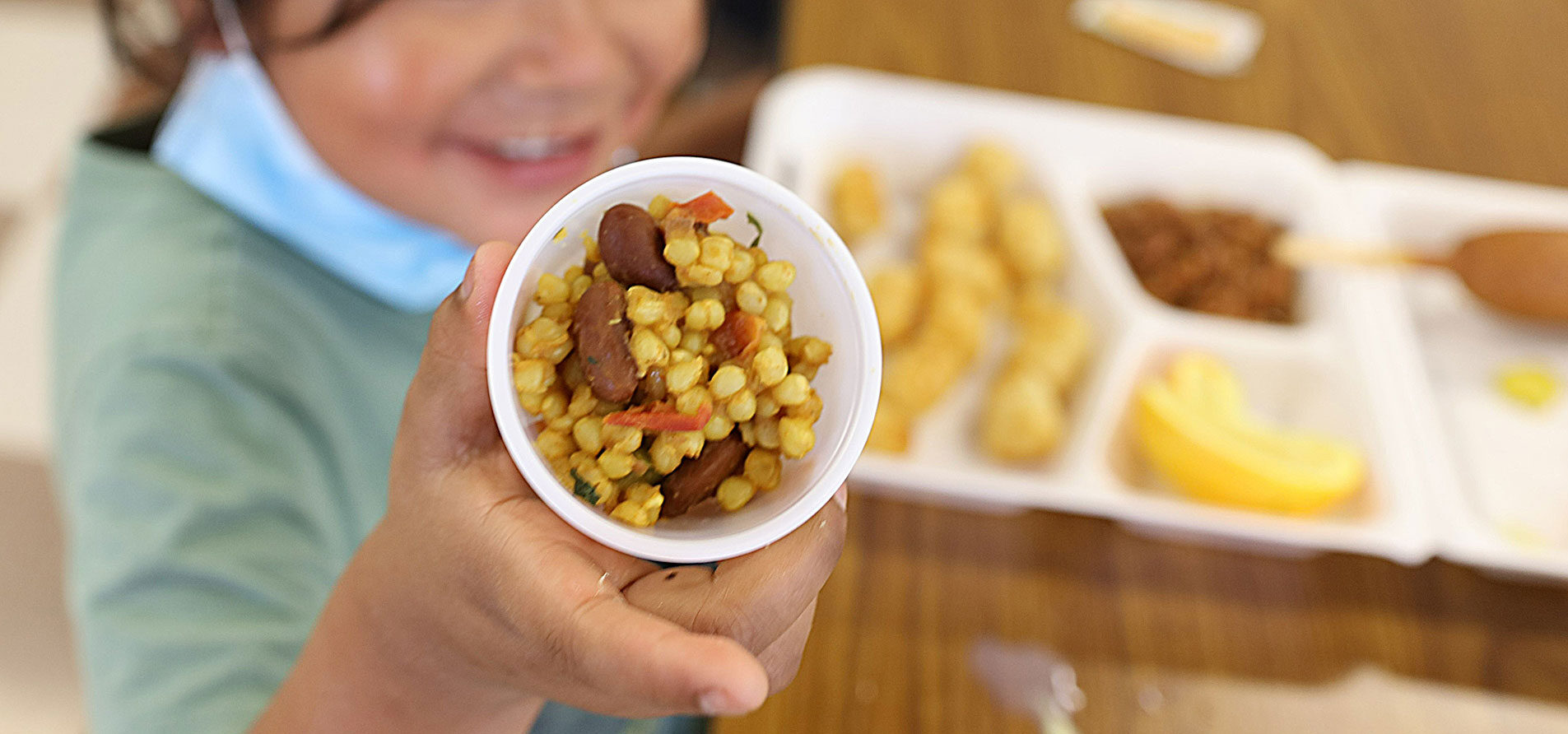 student holding a native school meal featuring corn